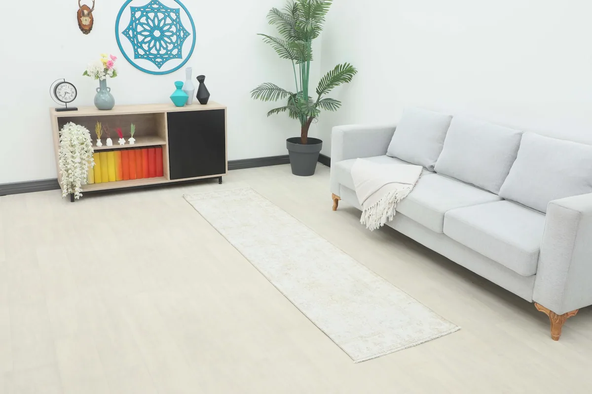 Ivory and beige runner rug styled in a modern living space next to a light gray sofa and wooden cabinet.