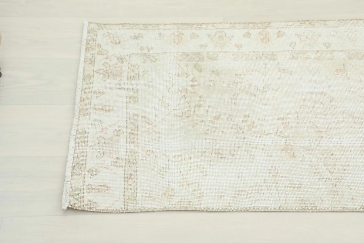Detailed view of the rug's faded patterns and subtle color variations near one end.