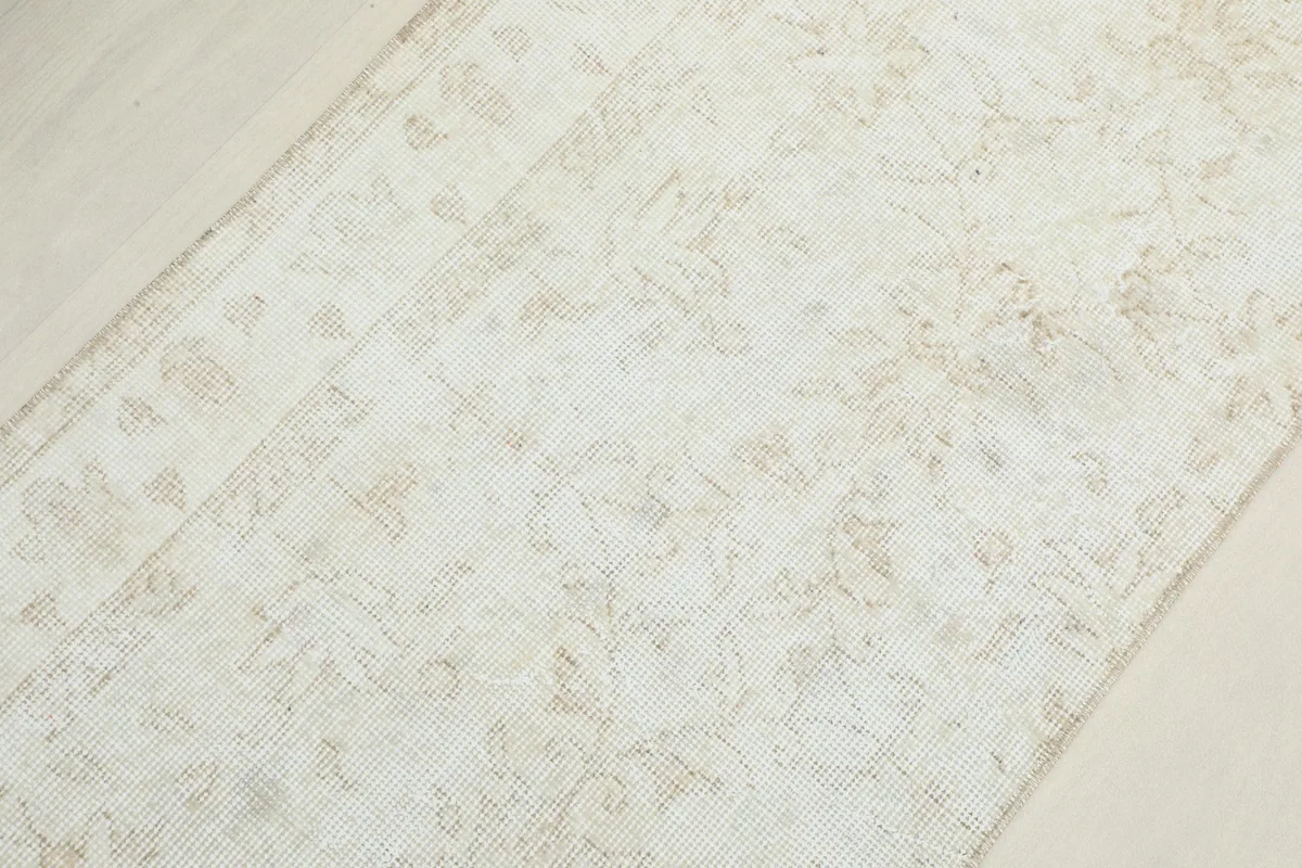 Overhead close-up showing the texture and faint patterns of the low-pile wool rug.