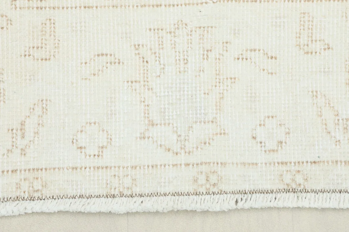 Close-up detail of the subtle tan floral and geometric patterns on the cream field.
