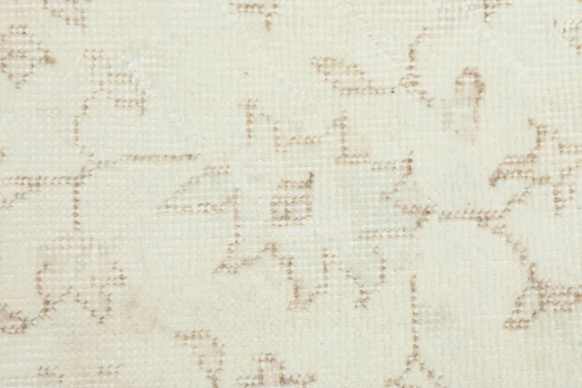 Detailed view of the hand-knotted wool pile and the intricate tan floral motifs.