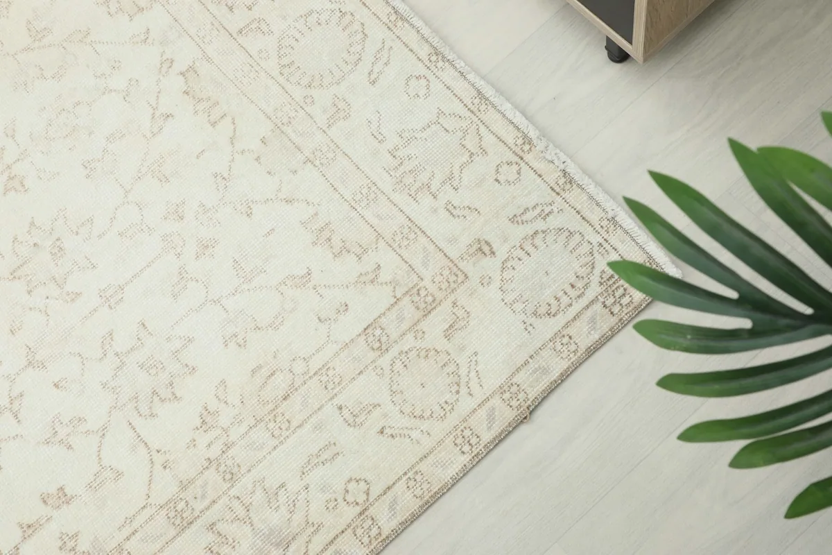 Close-up of the rug's border, featuring geometric patterns in tan against the cream background.