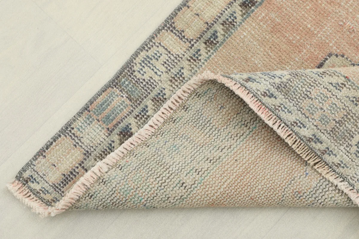Folded corner of the rug revealing the low pile and the hand-knotted construction.