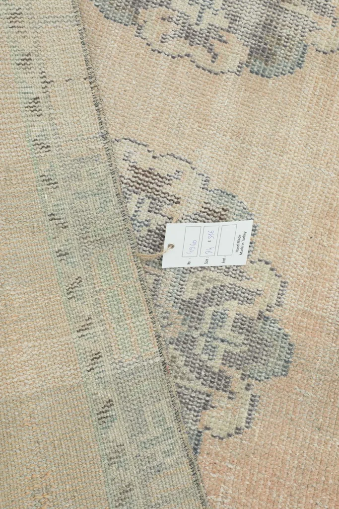 Back of the rug with a care tag, showing the intricate hand-knotted details.