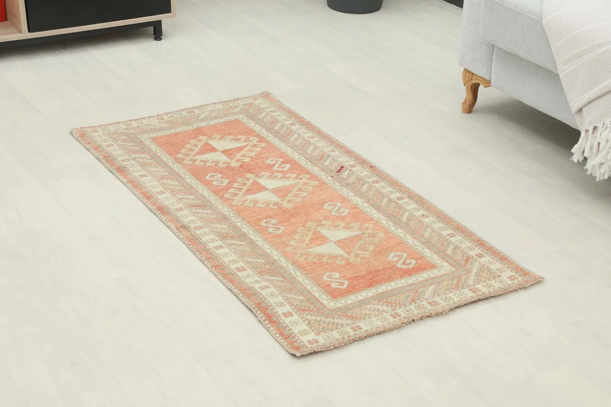 Angled view of the rug on a light floor, highlighting the rust and beige tribal design