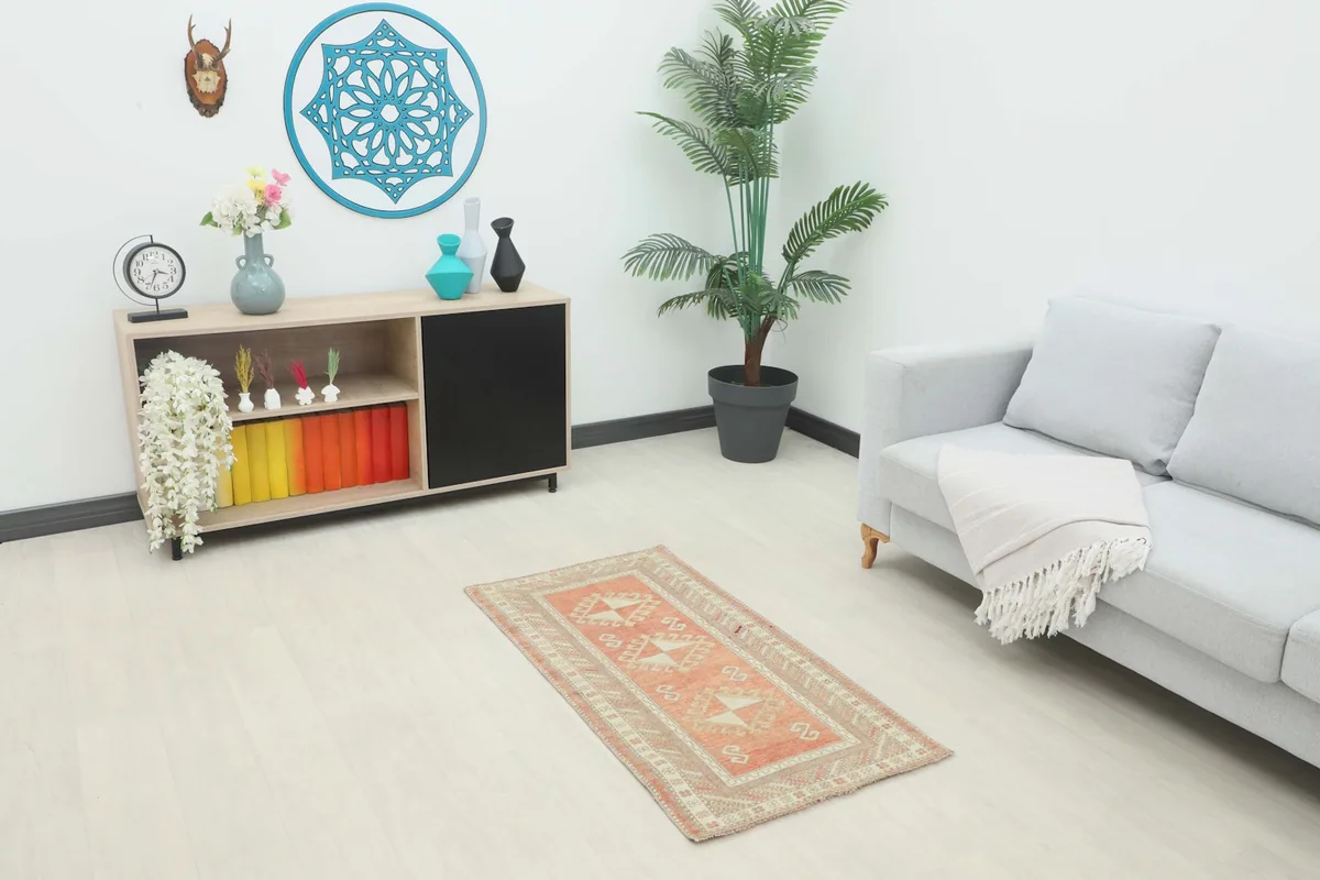 Vintage rug displayed in a living room setting, showing its scale next to a sofa and cabinet