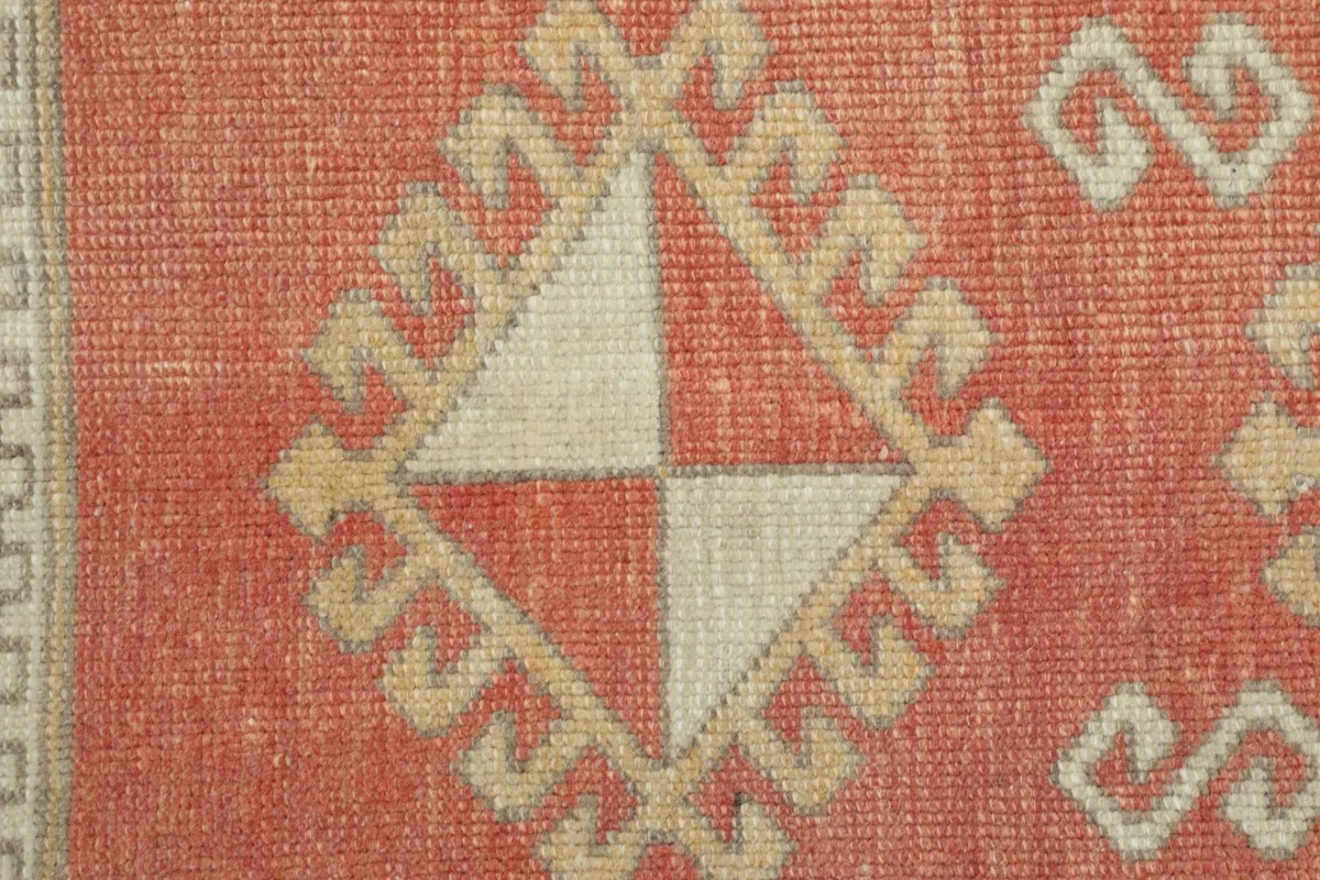 Extreme close-up of a beige and rust geometric motif, showcasing the hand-knotted texture