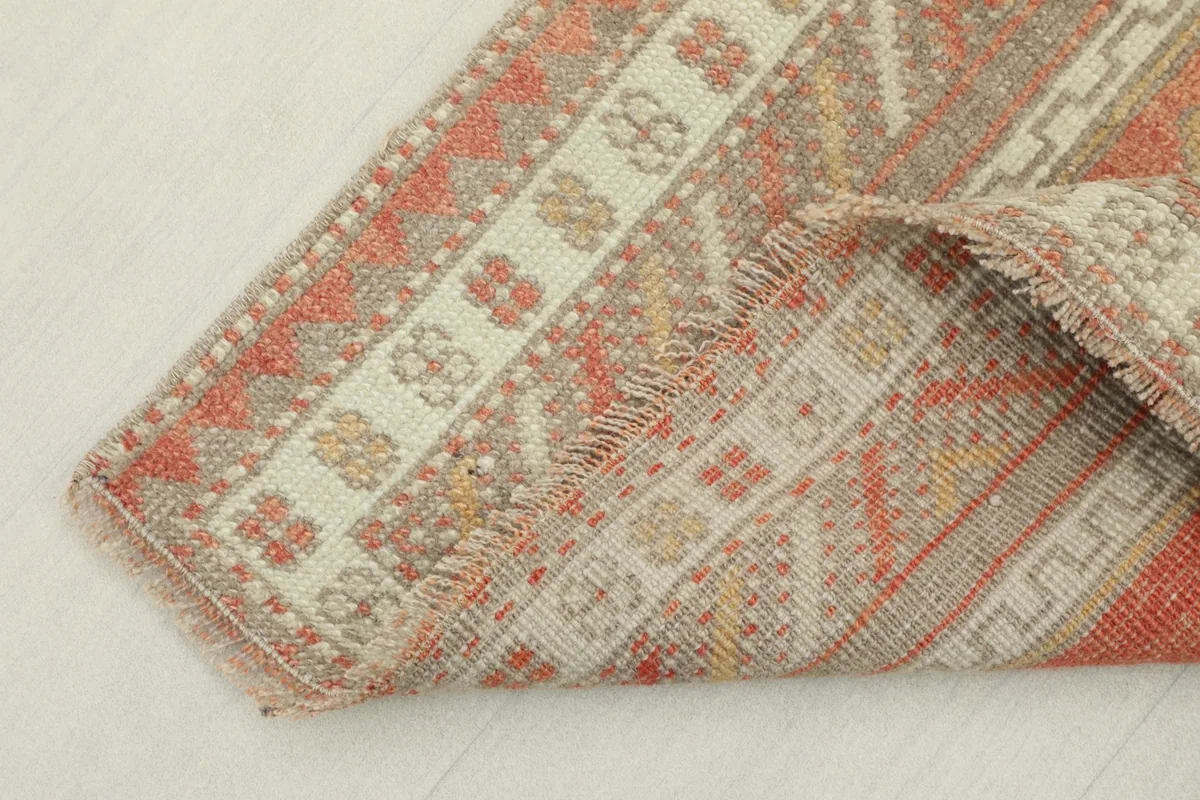 Corner of the rug folded to show the low wool pile and the construction of the border