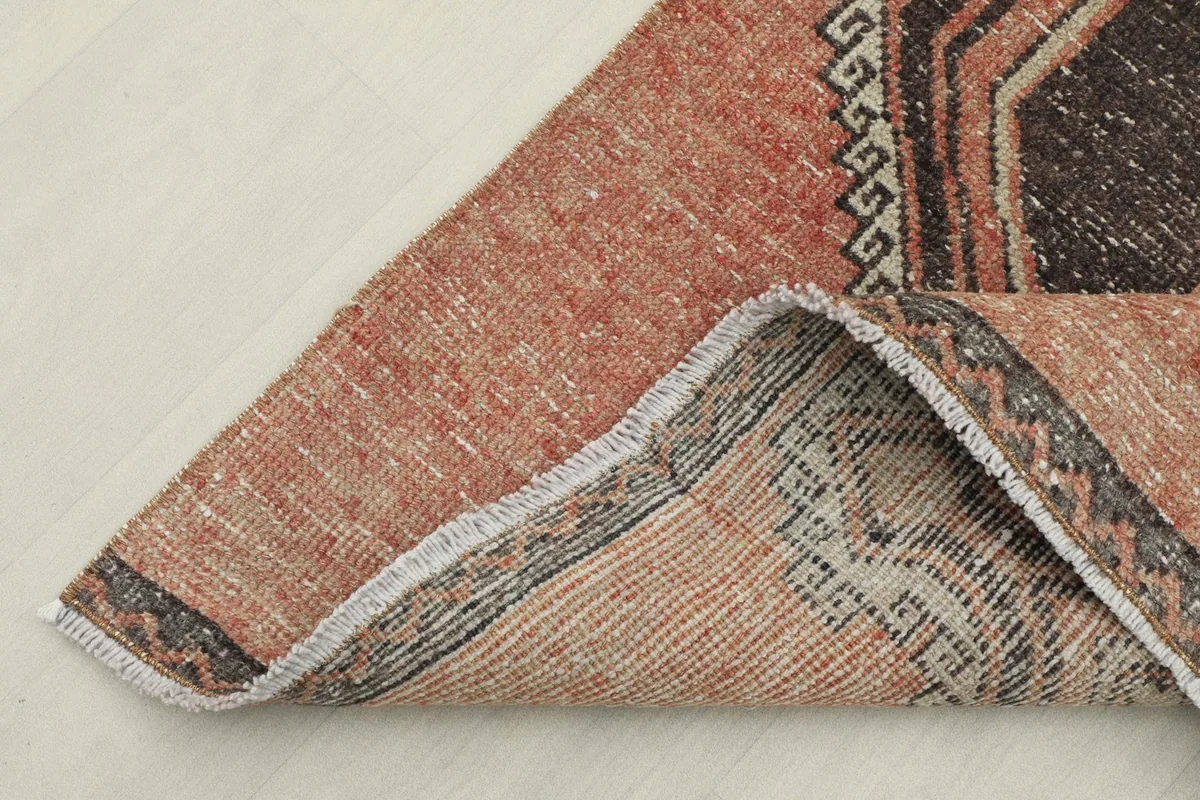 Corner of the rug folded to show the hand-knotted cotton foundation and wool pile