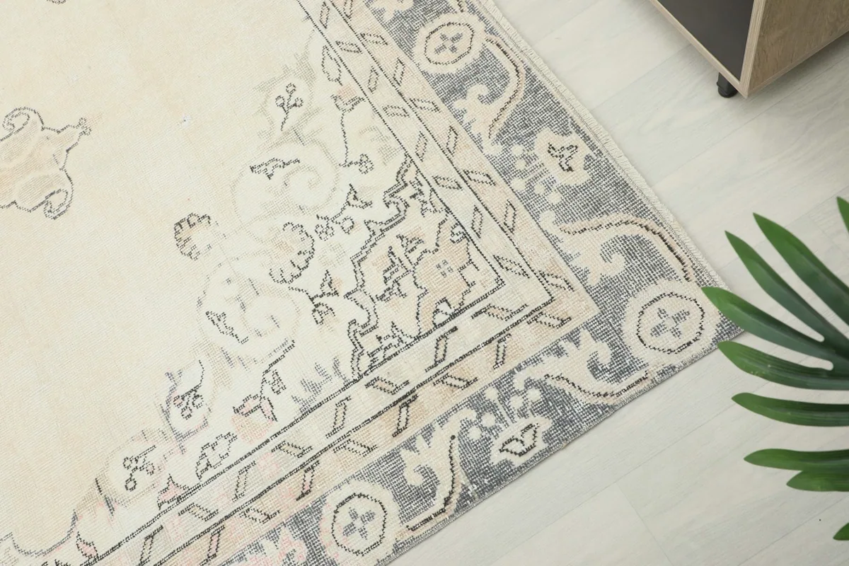Detail of the rug's outer border with gray and ivory patterns, showing slight wear.