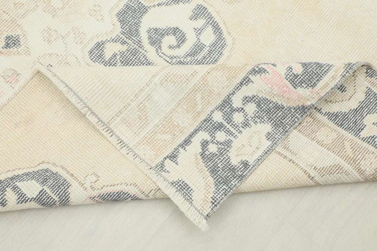 View of the rug's corner folded back, revealing the cotton foundation and hand-knotted construction.