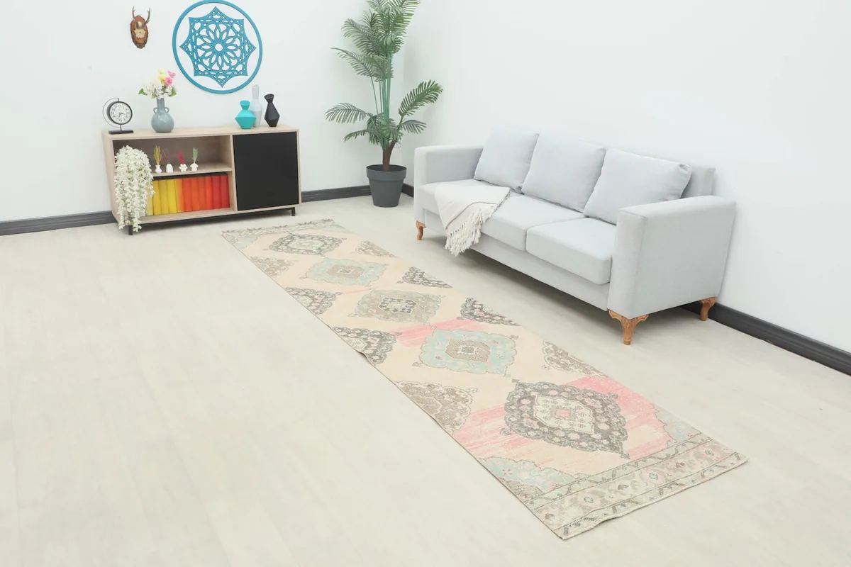 Vintage runner rug displayed in a room setting, showing its length and colors next to a sofa