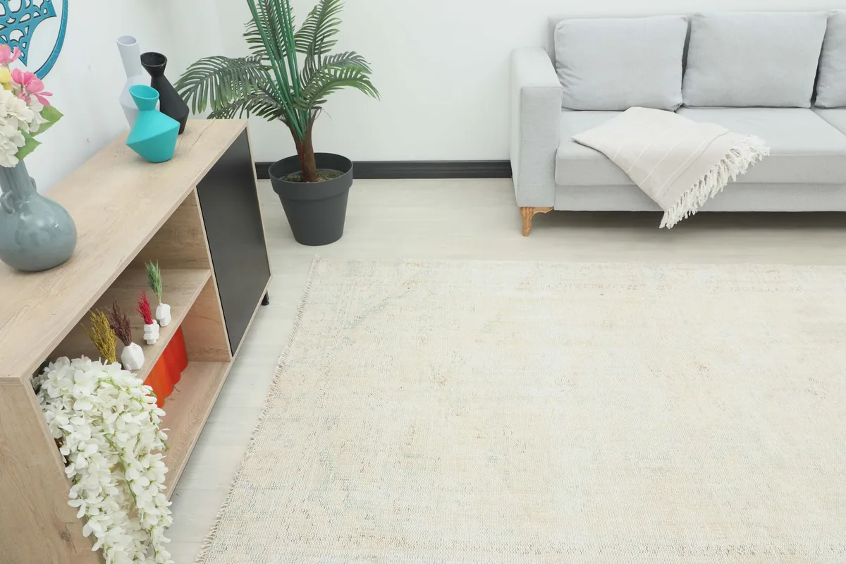 Angle view of the ivory area rug in a room, showing its placement relative to a sofa and decor.