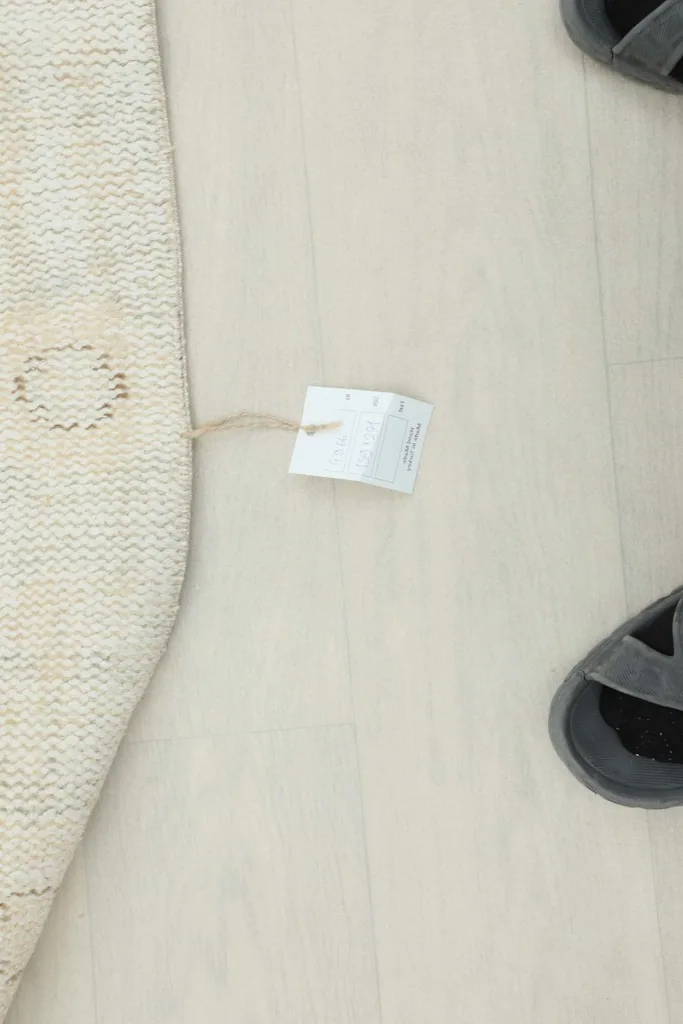 View of the rug's edge with a product tag attached, showing its authentic vintage nature.