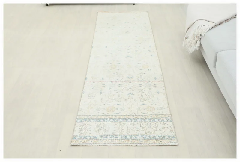 Full top view of the 2x8 ivory runner rug with blue and tan floral patterns on a white background.
