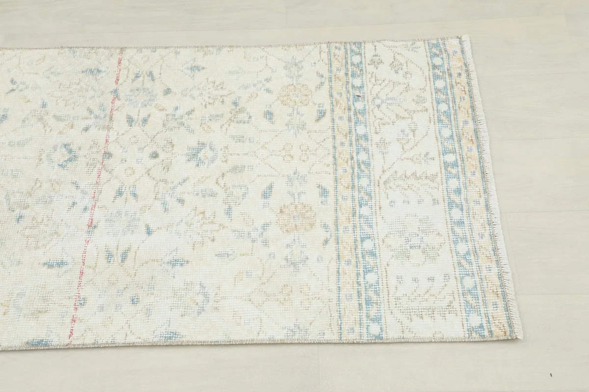 Close-up detail of the rug's border, featuring geometric and floral patterns in blue and tan.