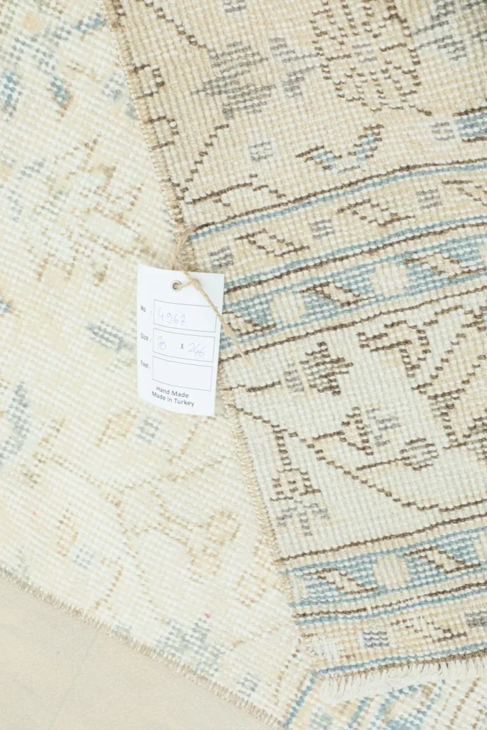 View of the rug's back and a tag, showing the tightly woven cotton foundation and craftsmanship.