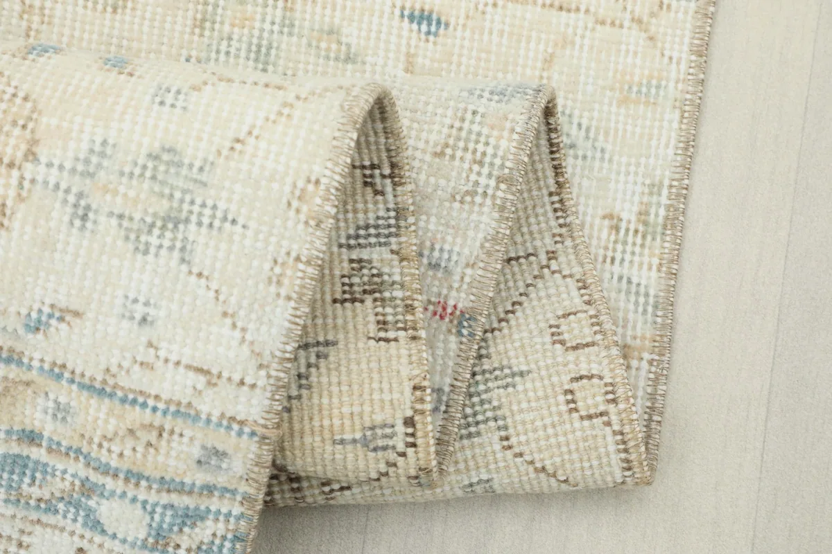 Close-up of the folded rug, revealing the intricate knotting and the texture of the wool pile.