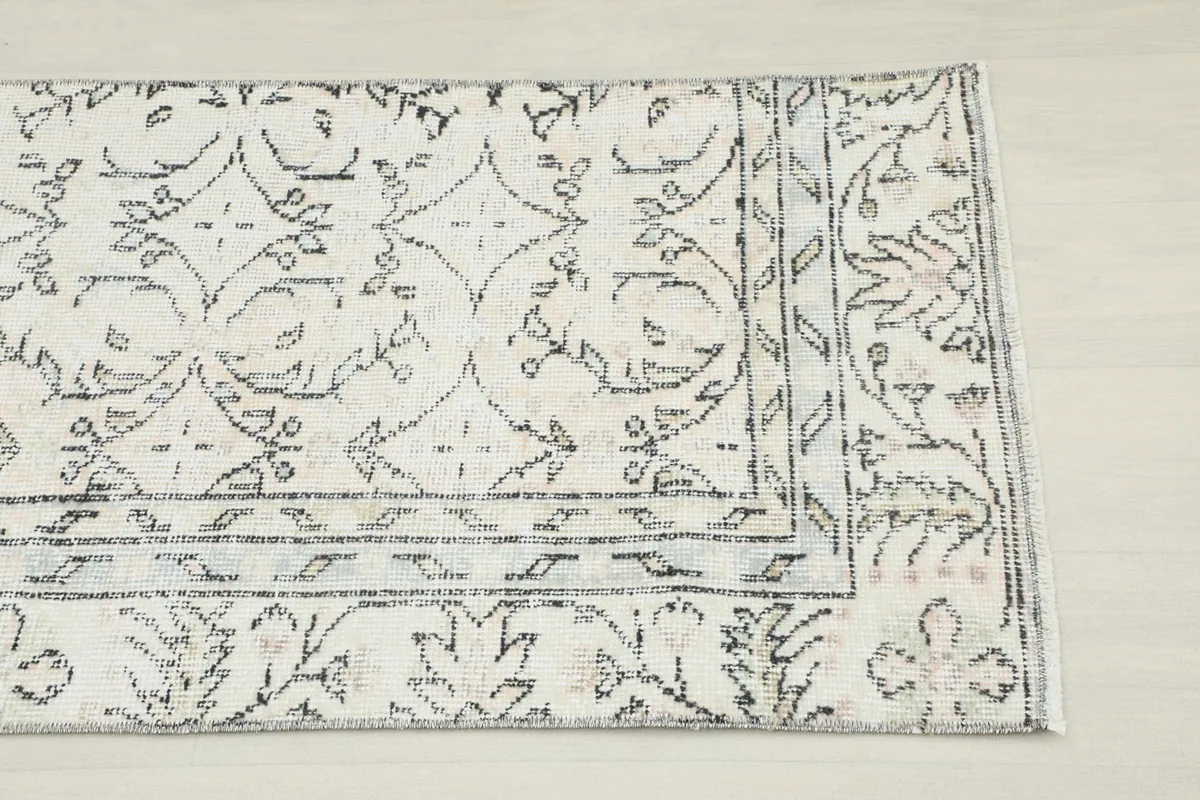 Close-up detail of the rug's corner, showing the charcoal geometric border and cream field.