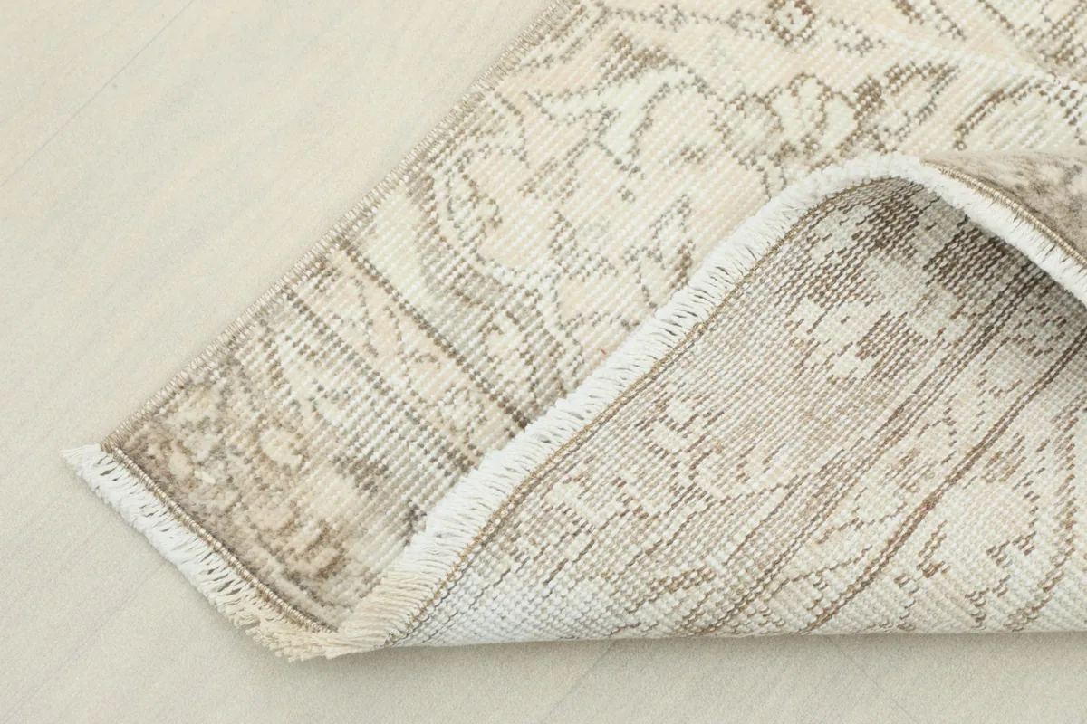 Corner of the rug folded back, revealing the backside of the hand-knotted construction.