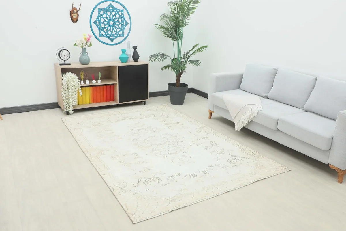 Vintage ivory rug displayed in a bright living room setting with a sofa and cabinet