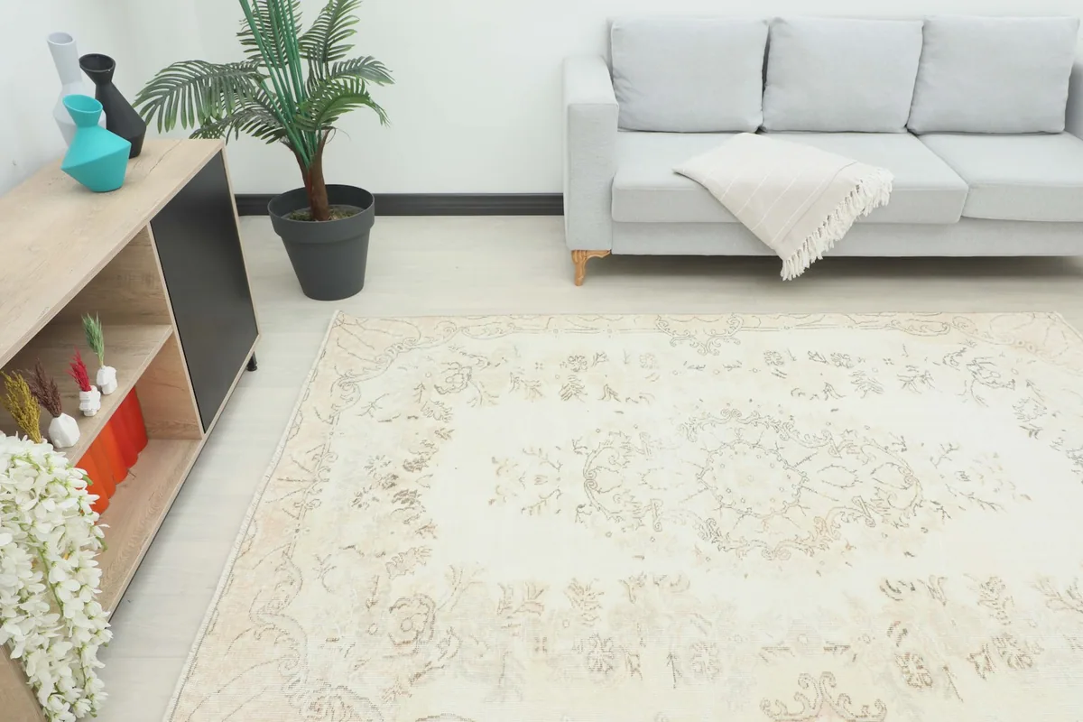 Angle view of the ivory vintage rug on the floor in a room, showing its overall placement
