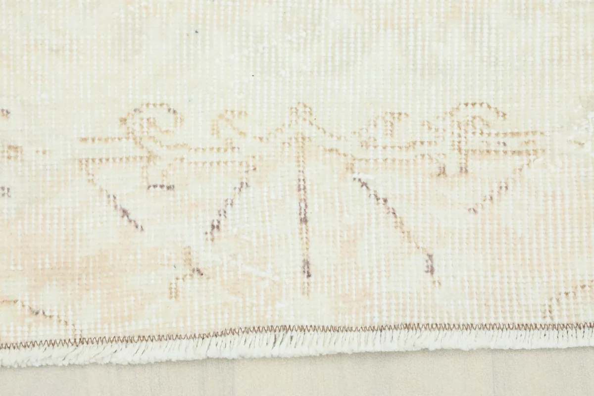 Close-up of the subtle tan and ivory pattern near the fringe of the hand-knotted rug