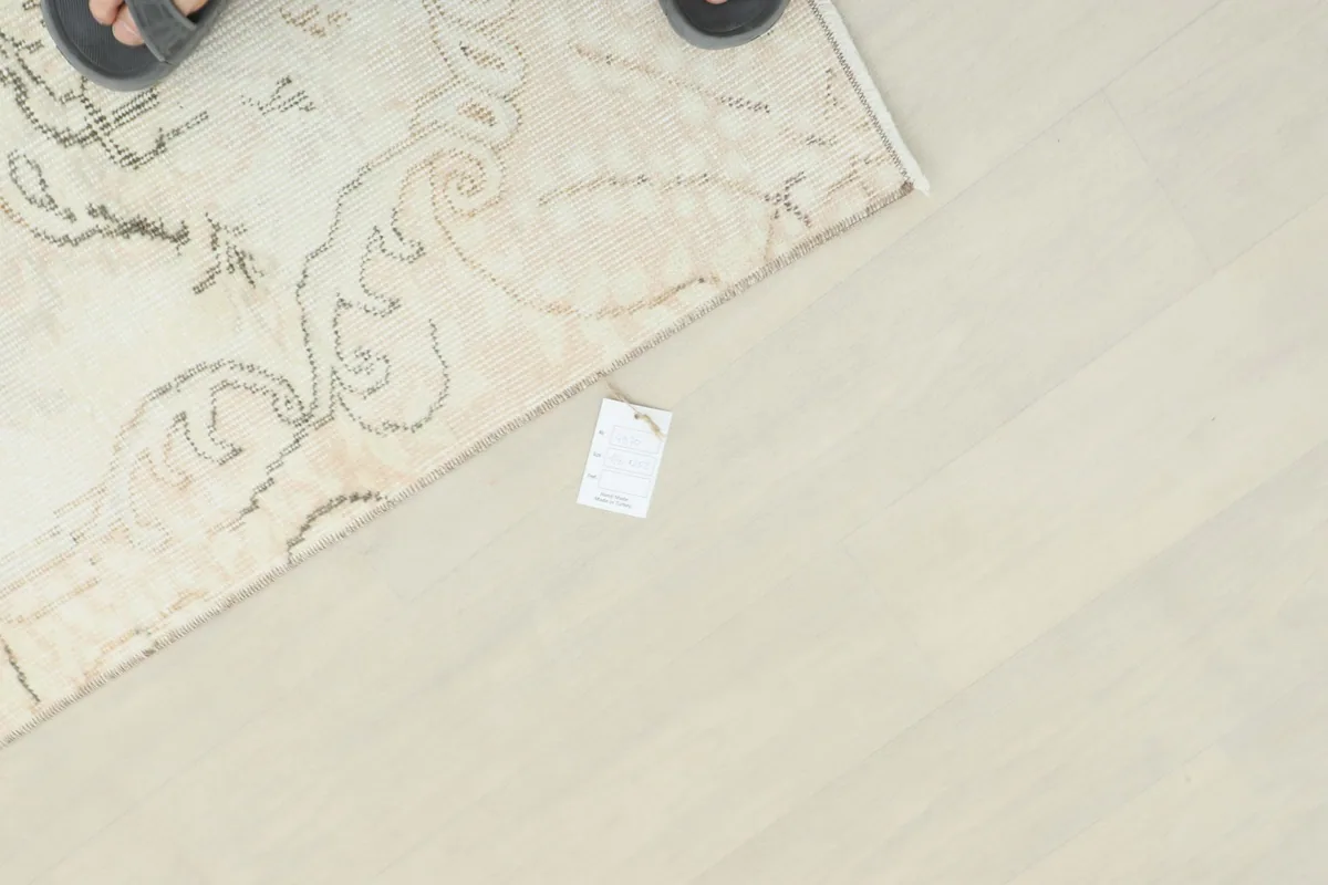 Overhead view of the rug's edge with a size tag, showing scale against a light floor