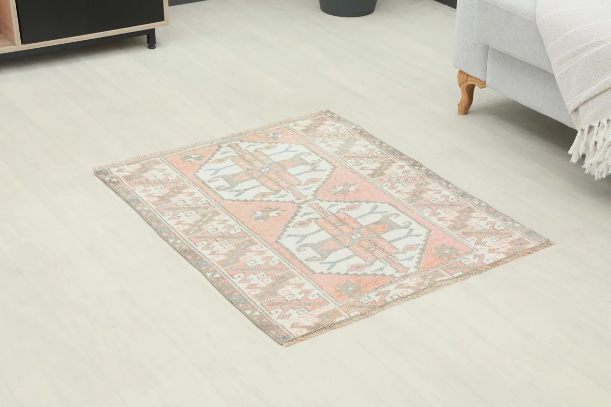 Angled view of the rose and ivory vintage rug showing its placement on a light floor.