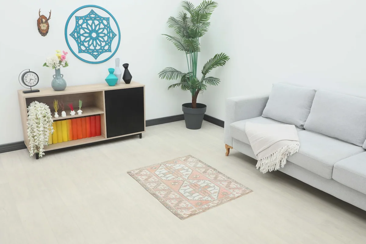 Room view of the rose and ivory vintage rug accenting a living space with a sofa and cabinet.
