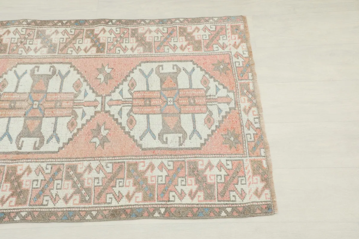 Close-up detail of the rose and ivory rug's central geometric patterns and border design.