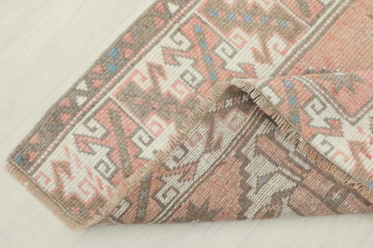 View of the rug folded back on itself, showing the border design and fringe texture.