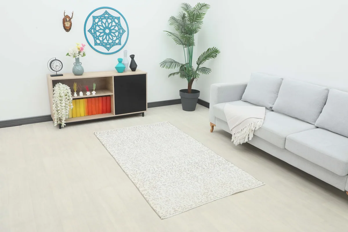 Ivory and tan floral vintage rug placed in a modern living room setting with a light gray sofa.