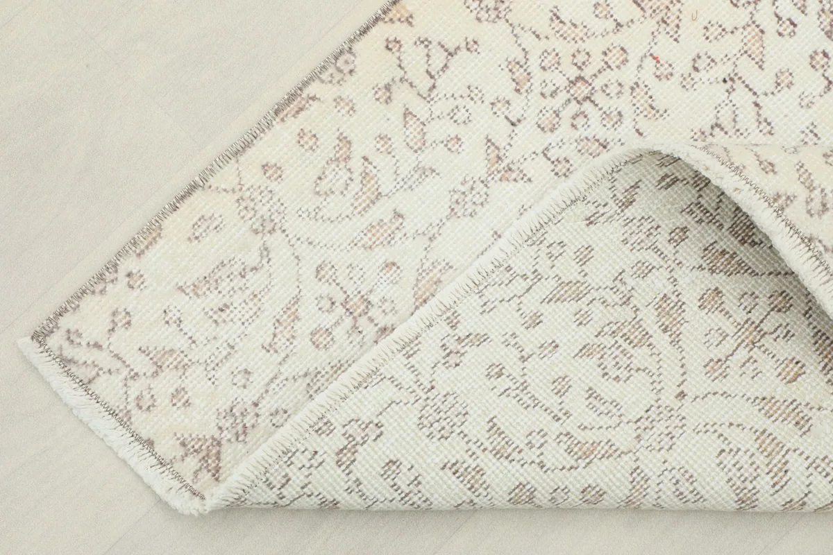 Corner of the rug folded back, showing the cotton foundation and the reverse of the knots.