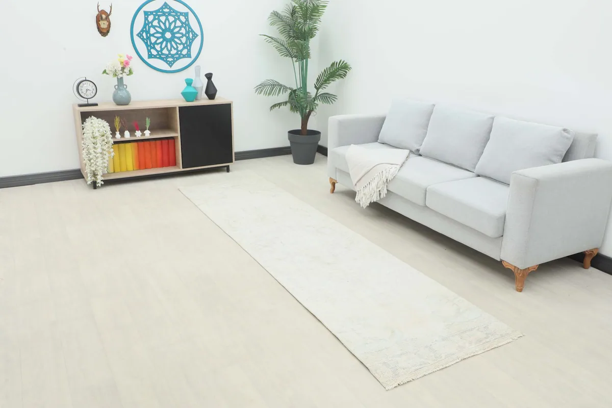 Runner rug placed in a living room setting, extending from a side table to a sofa