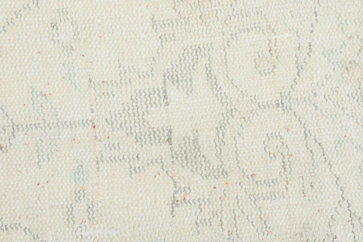 Macro view of the low wool pile, revealing the hand-knotted texture and faint color variations