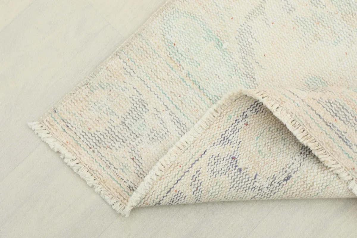 Corner of the rug folded to show the cotton foundation and reverse side of the hand-knotting