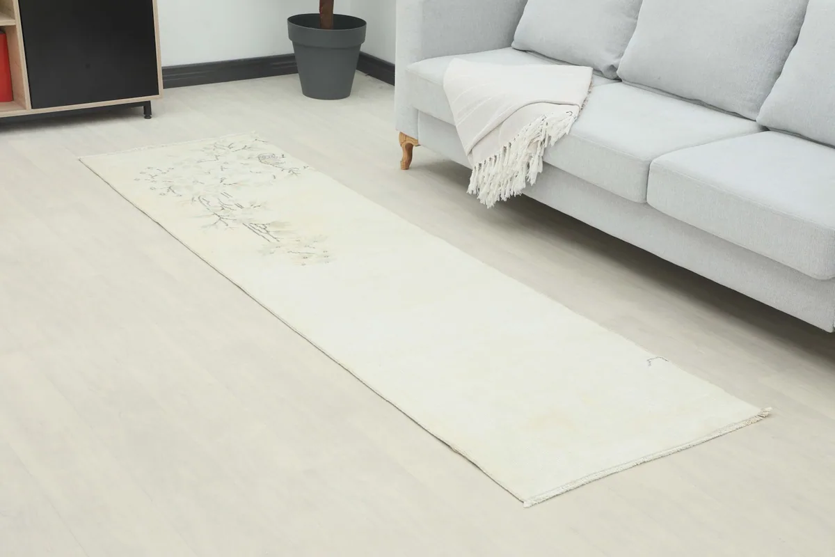 Angle view of the ivory runner rug in a room, showing its length and subtle design