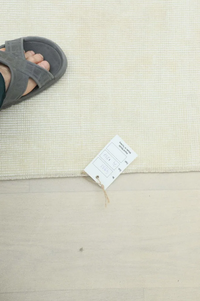 Foot in a sandal next to the rug to provide a sense of scale and texture of the low pile