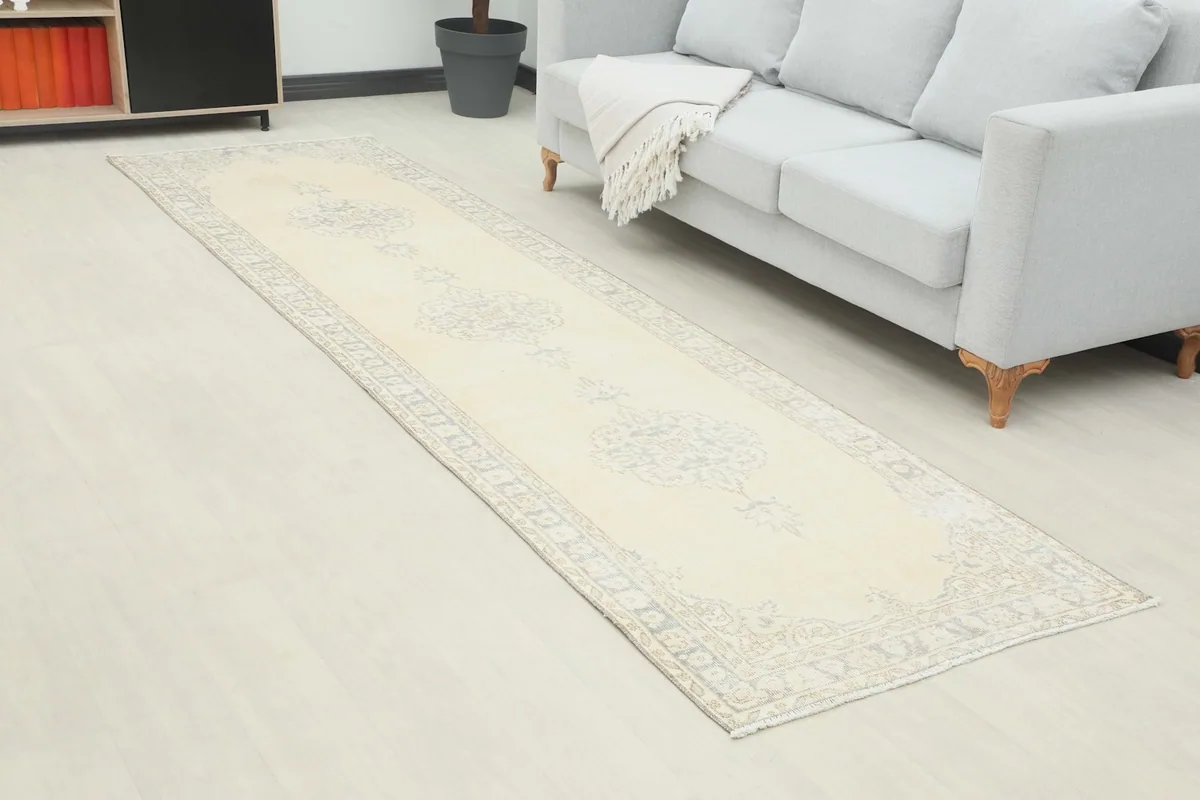 Close-up angle of the ivory and blue runner rug in a room, showing its length and pattern.