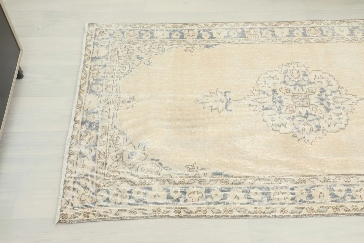 Detail of the rug's middle section, highlighting a faded blue medallion motif and border.