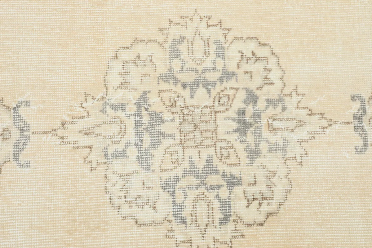 Tight close-up of a blue and gray medallion motif on the ivory field, showing wool texture.