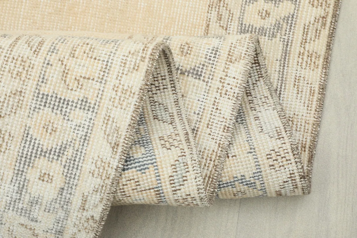 Close-up of the rug's reverse side and folded edge, showing the hand-knotted construction.