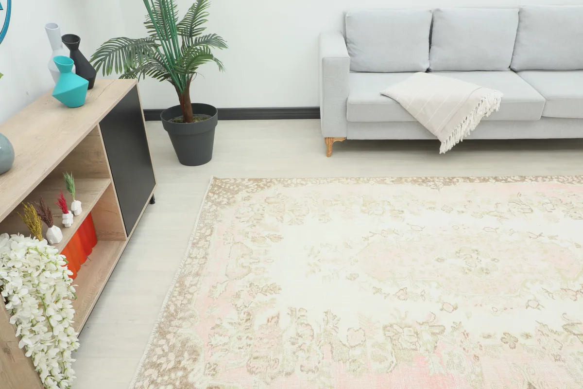 Soft Rose Floral Medallion Rug in a room with a gray sofa and a side table, showing its scale.