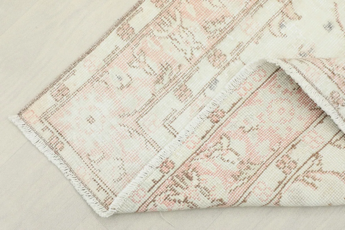 Corner of the rug folded to show the cotton foundation and reverse side.