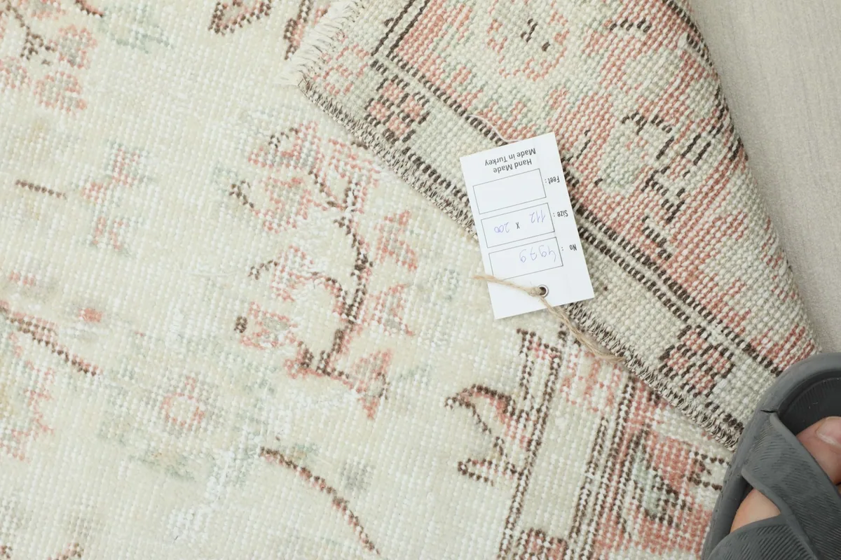 View of the rug with a tag showing size and origin details, next to a foot.