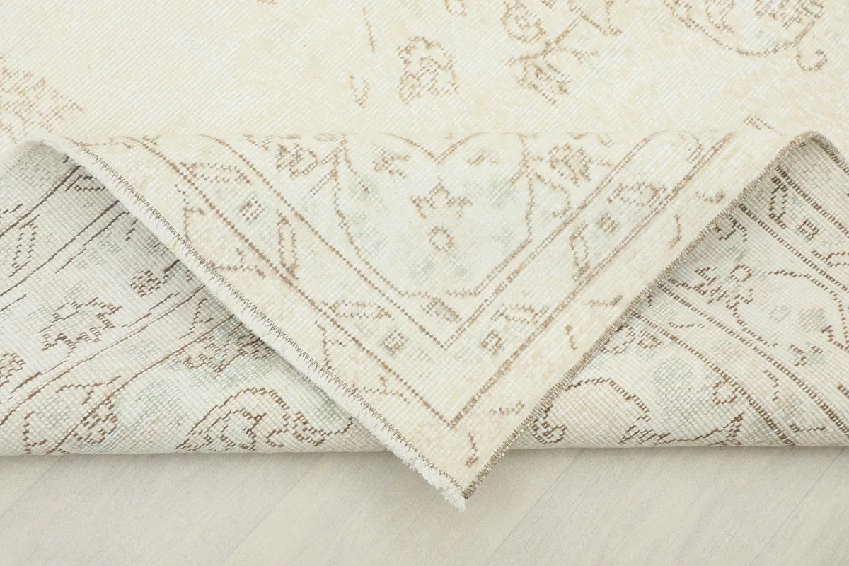 Folded corner of the rug, revealing the cotton foundation and the reverse side of the hand-knotted construction.