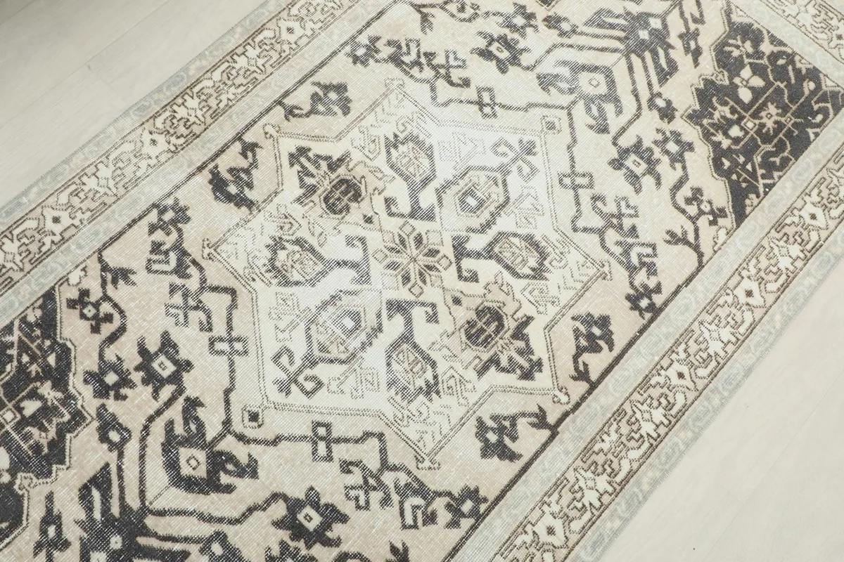 Detail shot of the central medallion and surrounding tribal motifs in cream and charcoal