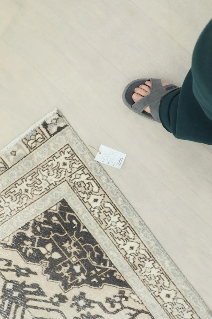 Overhead view with a foot for scale, showing the rug's size perception and tag