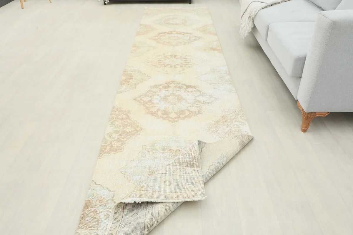 Long view of the runner rug partially rolled, showcasing its full length and pattern repeat.